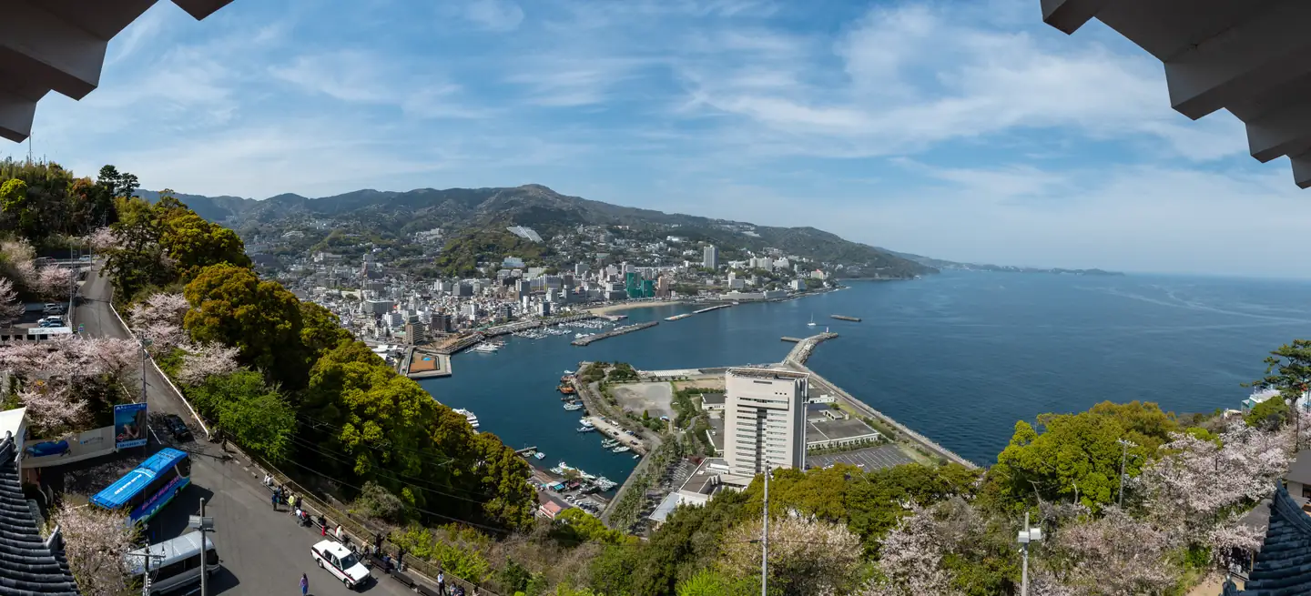 熱海城から北に望む熱海湾と市街地。海岸に沿って建物が並ぶ実景。