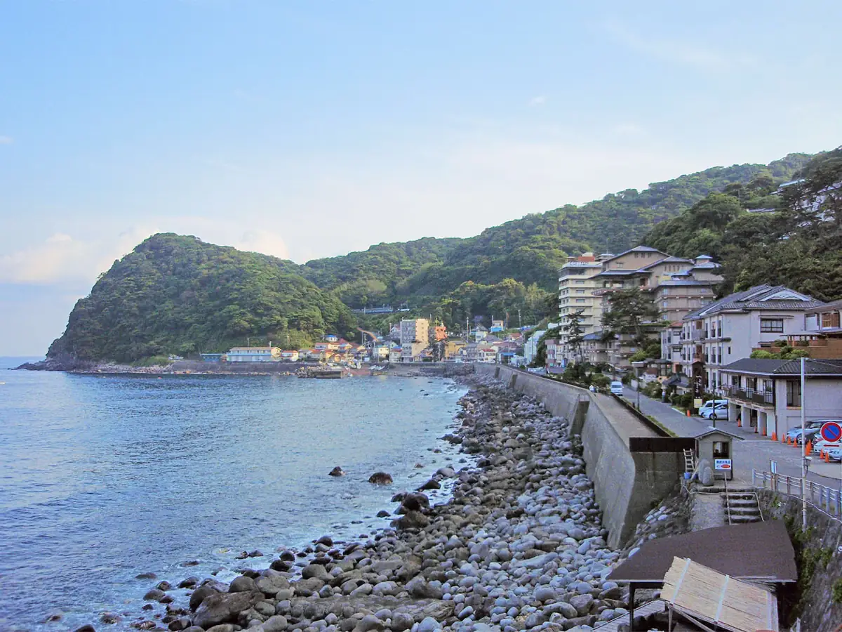 静岡県東伊豆町の北川温泉。海沿いの道路と温泉街、緑の山が見える実景。